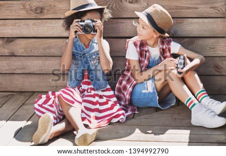 Beautiful little girls taking pictures with photo cameras. Cute smilling happy girls playing outdoors