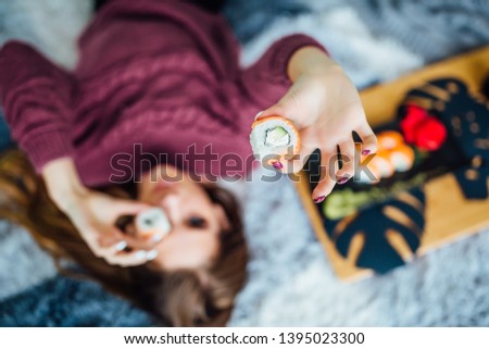 Focus at sushi roll. Young girl lying in bed with food