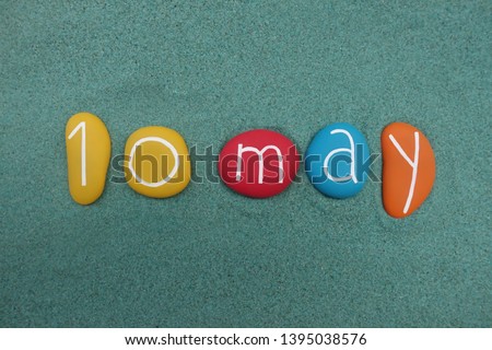 10 May, calendar date composed with multi colored stones over green sand