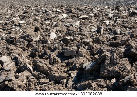 Deeply plowed clay in a field in Oregon leaves huge clods of dirt, some shining in the sun with smooth, cracked surfaces, images for rough and rugged backgrounds.