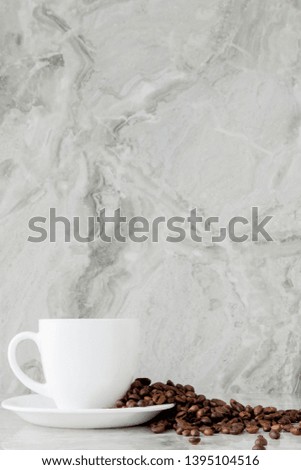 Black coffee in cup and coffee beans on marble background. Top view, space for text.