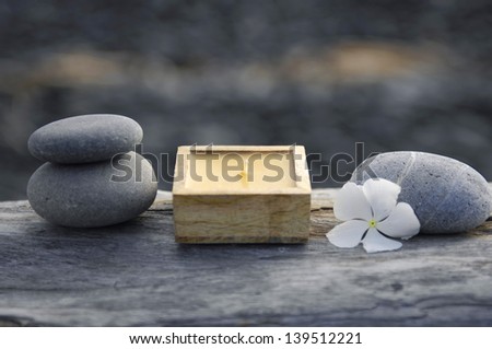white flower with candle, stones on driftwood texture