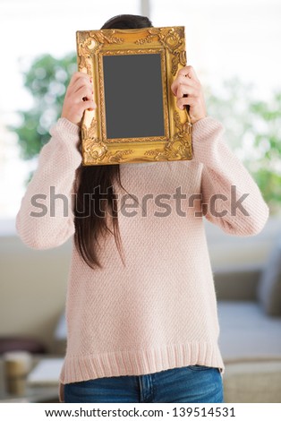 Woman Hiding Face With Picture Frame, Indoors
