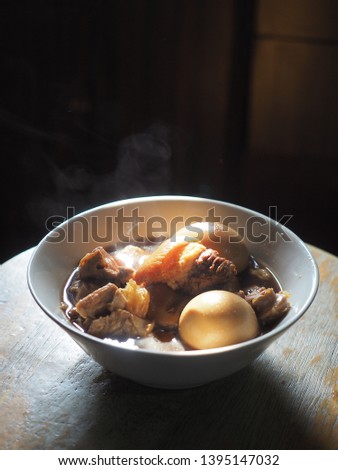 Hot bowl of Thai stewed pork leg and eggs with smoke.