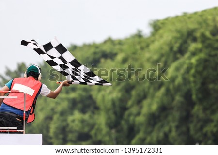 Back view of man holding checkered race flag Royalty-Free Stock Photo #1395172331