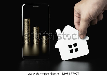 Smartphone with coin stack and house icons model, house for rent, house selection, application for online searching, buying, selling and booking real estate.