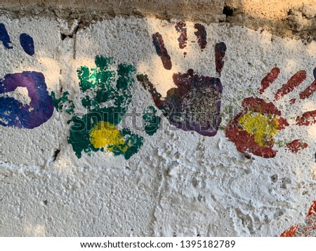 Children's hands painted on the wall and anonymous drawings.