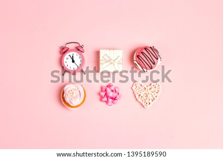 Set of tasty cupcakes, alarm clock, gift and heart on pink pastel background. Romantic love background. St. Valentine, Mothers, Womens Day concept. Copy space, overhead shot. 