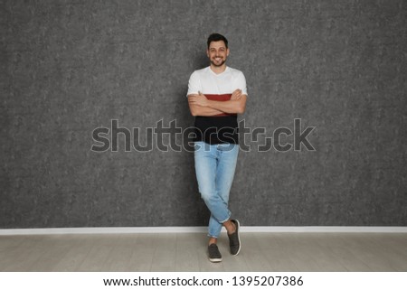 Full length portrait of handsome man against grey wall