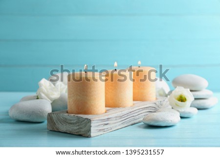 Composition with burning candles, spa stones and flowers on table. Space for text