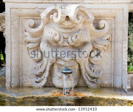 Color DSLR picture of marble fountain in the shape of the head of a man in the gardens of the Galleria Borghese, Rome, Italy. Water is spewing from mouth of figure. 