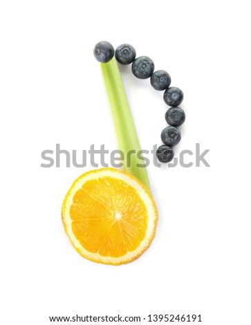 Musical note made of lemon, celery and berries on white background, top view