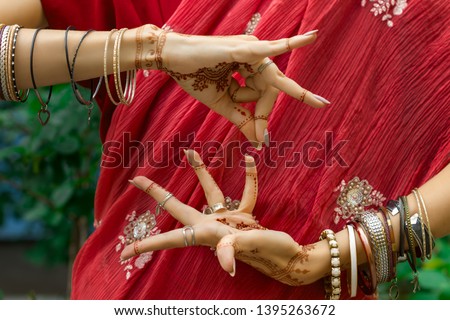 Beautiful woman in traditional Muslim Indian wedding pink sari dress with henna tattoo jewelry and bracelets do hands nritta odissi Samyuta hastas dance Movement Alapadma Bramara Concept background