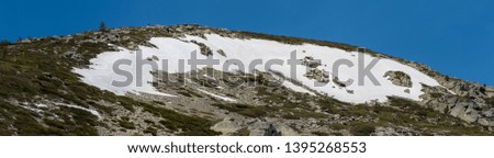 Panoramic landscape of high mountain in spring, with small snowfields. Natural Park of the Sierra de Guadarrama, Madrid, Spain