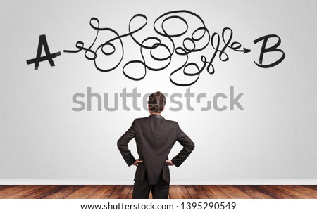 Businessman looking for connection between two things while standing in front of a wall