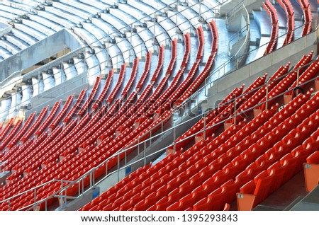 Rows of orange plastic seats on a grandstand, pattern of folding chair in a stadium, sitting area for spectator
