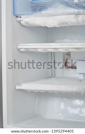 ice in the freezer. icing cooling tubes. refrigerator requires defrosting. repair of the freezer. empty fridge, lots of ice in the freezer Royalty-Free Stock Photo #1395294401