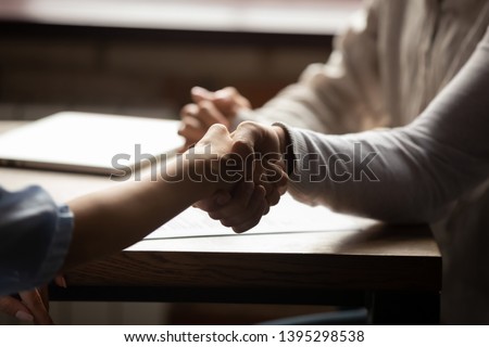 Close up couple handshaking businesswoman in cafe, making successful deal, signing contract, family purchasing real estate, taking loan or mortgage, man shaking hand of realtor or broker