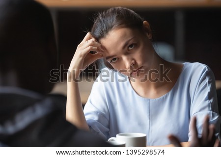 Bored unhappy girlfriend listening to African American boyfriend in cafe, bad first impression and date concept, multiracial couple having sitting at table, talking, having problem in relationships Royalty-Free Stock Photo #1395298574