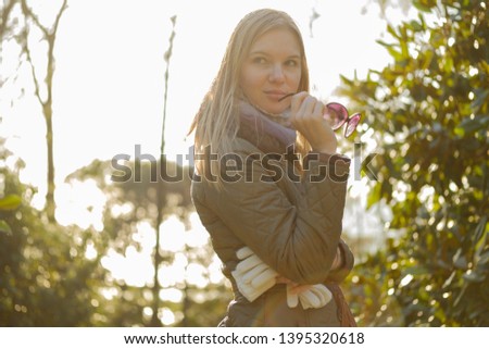 Beautiful blond girl posing for photo at sunny day in cold weather coat