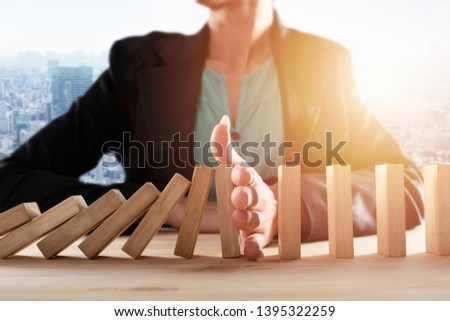 Businesswoman stops a chain fall like domino game. Concept of preventing crisis and failure in business. Royalty-Free Stock Photo #1395322259