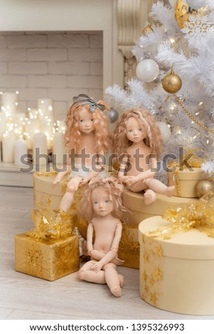 three dolls made by hands from textiles are very similar to living people. designer dolls sit on boxes with gifts under the Christmas tree. creation of dolls for the new year holiday