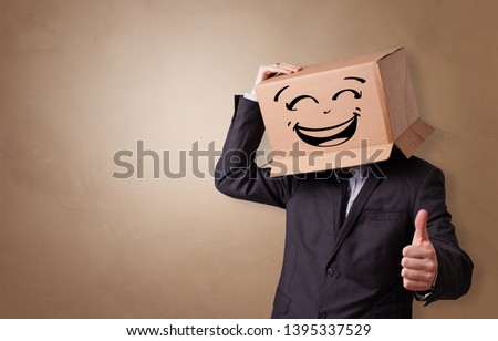 Young man with happy face illustrated cardboard box on his head
