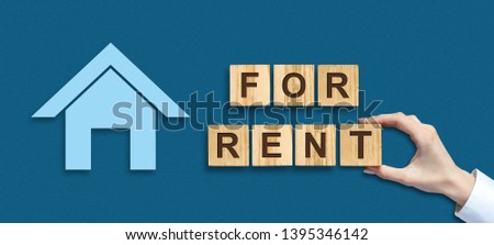 Concept rent. Female hand and the inscription For Rent on wooden blocks. Business and Finance. Background.