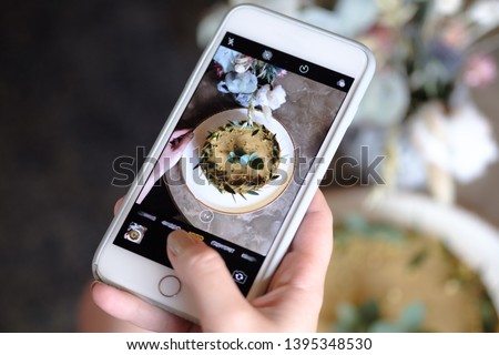 food, eating, technology, culinary and people concept - woman hands with cheesecake photo on smartphone screen at restaurant