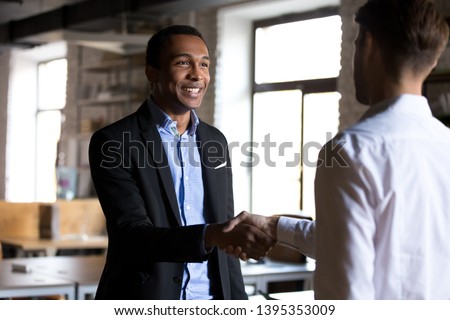Diverse business partners two businessmen shaking hands meets at office for negotiating signing contract reach common goal. Human resources hiring, client and representative, respect and trust concept