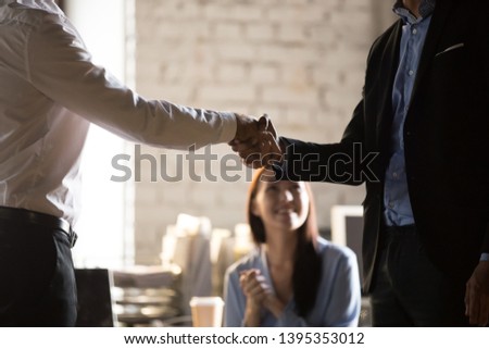 Close up two businessmen standing in office shaking hands. Boss congratulating successful employee with reward great result at work, monetary bonus,  promotion or new workers first impression concept Royalty-Free Stock Photo #1395353012