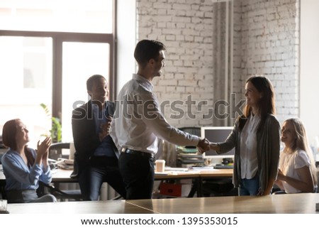Diverse staff applaud to colleague female, company ceo boss congratulate good work result handshake with woman worker with promotion bonus reward girl feels happy gratitude support of newcomer concept Royalty-Free Stock Photo #1395353015