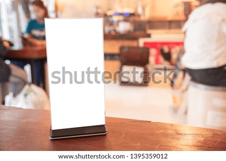 Mock up Menu frame in Bar restaurant, Stand for booklets with white sheets of paper acrylic tent card on wooden table on cafeteria blurred background. 