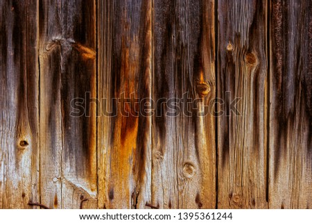 Weathered planks with footprints of fire on its surface closeup background