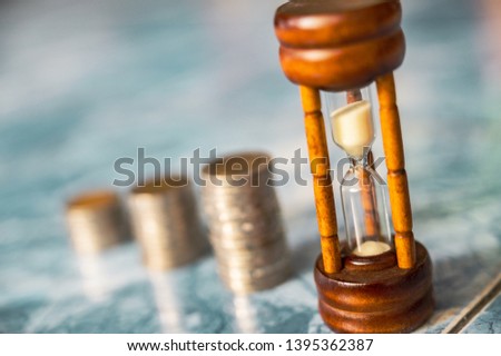 step of coins stacks with sandglass or hourglass, saving and investment or family planning concept, motion blured background.