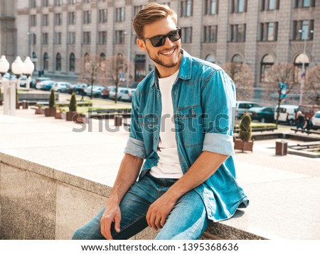 Portrait of handsome smiling stylish hipster lumbersexual businessman model. Man dressed in jeans jacket clothes. Fashion male posing on the street background in sunglasses Royalty-Free Stock Photo #1395368636