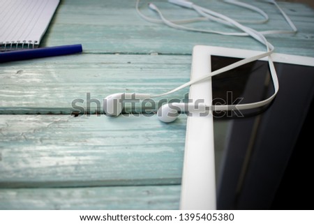 phone headphones, notebook, tablet and pen on the desktop