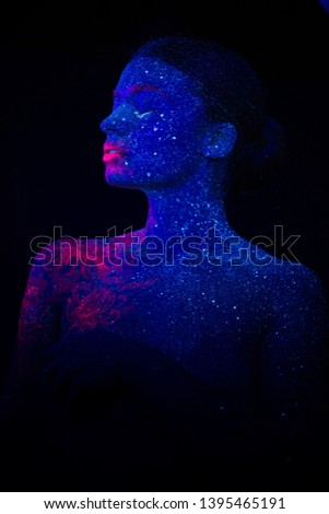 Picture of a pink jellyfish on the shoulder and face of the beautiful woman. ultraviolet body art. The girl turned her head in profile and up.