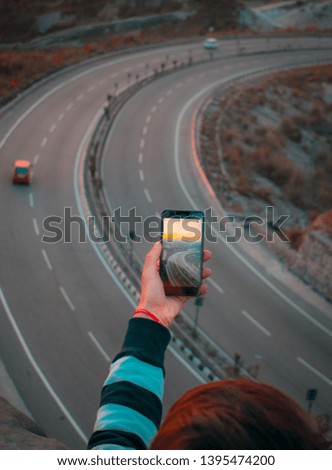 Mirror photo of highway in a phone screen. Boy looking at his phone over a beautiful highway