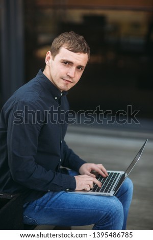 Happy young man typing something on his laptop and smile