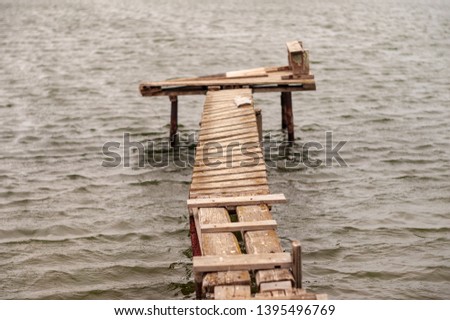 Wooden bridge for fishing on the river is destroyed after winter and spring high water. Notion of damage, deformed, destroyed, and dilapidated. Concept destruction of hopes