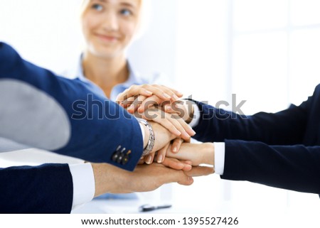 Business team showing unity with their hands together. Group of people joining hands and representing concept of friendship, teamwork and partnership