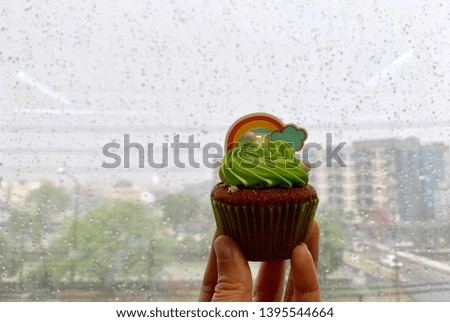 One cup of rainbow cupcakes in the back of the hand is a mirror filled with rain, Blurred picture.