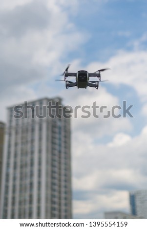 Flying drone against the sky with clouds and buildings.