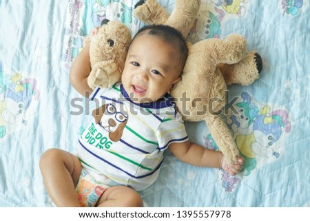 Toddler smiling asian child boy lying on bed enjy with doll