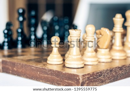 Old well used wooden chess pieces on a chessboard, retro leadership concept on white background