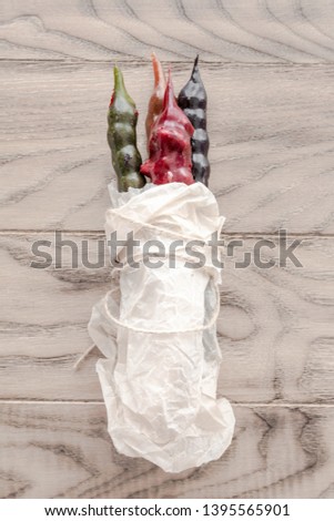 Colorful ancient Georgian national sweet churchkhela, different colours, in white cooking paper. Vertical image. Wooden background.  Top view, flat lay. Copy space.