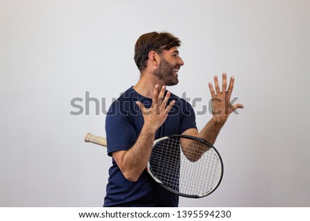 Photography of a handsome young man playing tennis motioning to come here with a finger, facing forwards and looking at the side