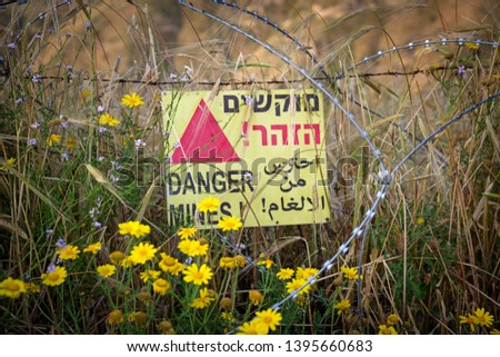 Danger mines - yellow warning sign next to a mine field, close to the border with Syria, in the Golan Heights, Israel.