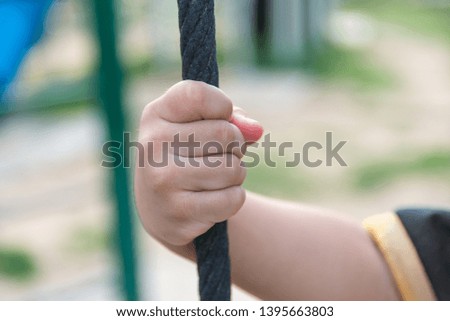 The boy tightened the large rope to prevent himself from dropping. With the right hand beside the right, he will climb higher up without giving up